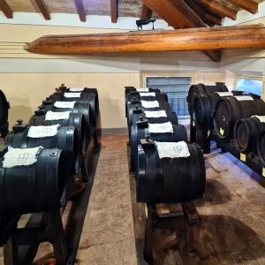 cantina con alcune file di botti in legno per l'affinamento dell'aceto balsamico, posizionate su appositi supporti in legno a circa 50 cm. dal suolo.