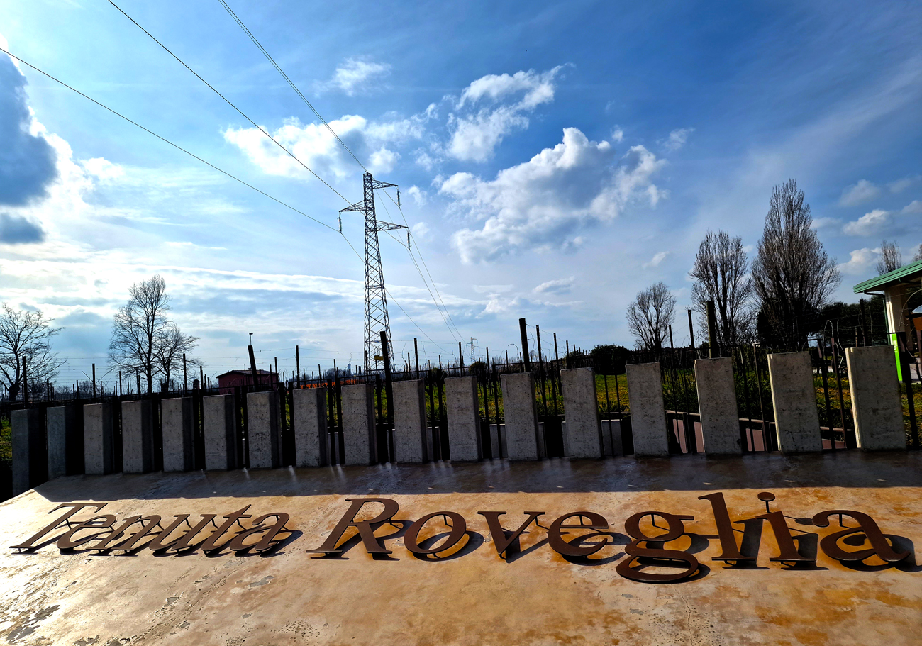 Insegna della Tenuta Roveglia in Lugana con cielo blu e nuvole sullo sfondo.